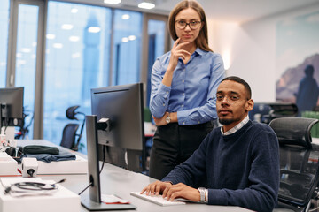 Fototapeta premium Digital Collaboration: Blonde Businesswoman and African American Partner Reviewing Documents Online