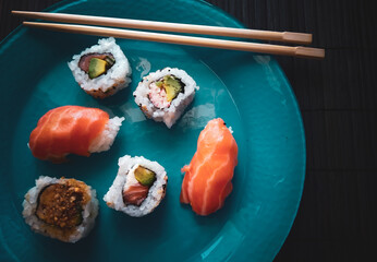 niguiri, hossomaki, variety of japanese food on blue plate with chopsticks