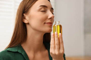 Fototapeta premium Aromatherapy. Beautiful woman with bottle of essential indoors
