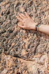 Woman hand with different bracelets on the old stone wall