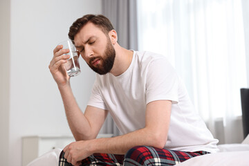 Young man suffering from headache on bed at morning
