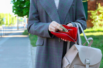 Woman holding purse with banknotes outdoors, closeup. Space for text