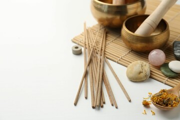 Incense sticks, Tibetan singing bowls, stones and dry flowers on white table, space for text