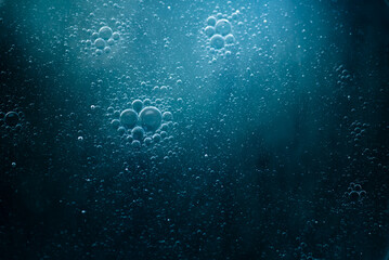 Fototapeta premium Air bubbles in the water background.Abstract oxygen bubbles in the sea.Water bubbles isolate on blue background.Sunlight underwater with bubbles rising to water surface in the sea
