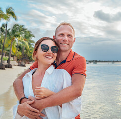 Couple in love hugging on the sandy exotic beach while they have a evening walk by the Trou-aux-Biches seashore on Mauritius island. People relationship and tropic honeymoon vacations concept image.