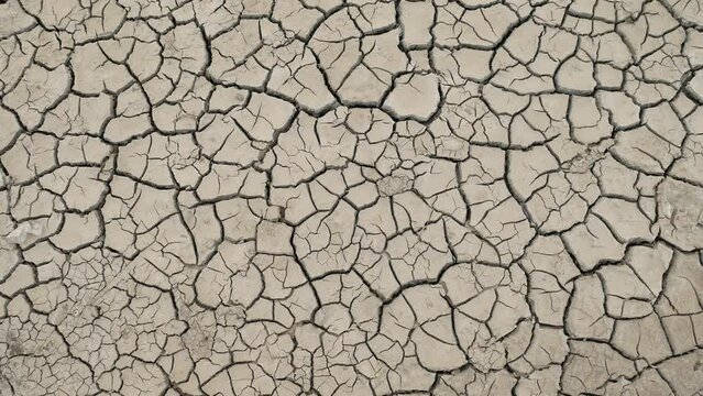 The dry, cracked ground stretches endlessly, a testament to the severe lack of water. The soil is parched and split, with no vegetation or moisture visible, indicating a prolonged drought
