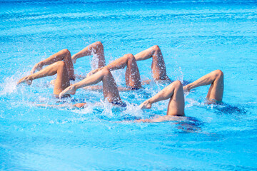 Artistic swimming team performing synchronized legs movement in swimming pool
