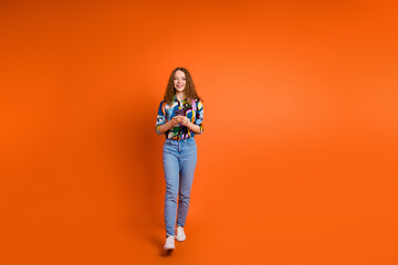 Fototapeta premium Photo of pretty cute girl dressed stylish clothes hold use modern gadget isolated on orange color background