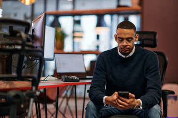 After Hours Reflection: African American Man Using Smartphone in Office.