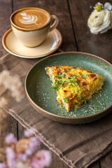 Slice of Spanish zucchini tortilla with a cappuccino on the coffee shop table.  Brunch food.