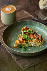 Slice of potato and spinach tortilla with a cappuccino on the coffee shop table.  Brunch food.
