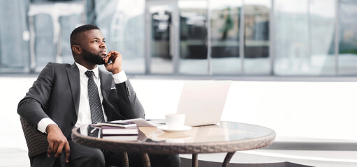 Thoughtful African American Businessman Sitting At Laptop Touching Chin In Outdoor Cafe. Strategic...