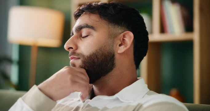 Thinking, man and sad on sofa with stress from bad memory, mistake and news in living room. Indian guy, anxiety and thoughts at home with depression, regret and mental health or lonely for reflection