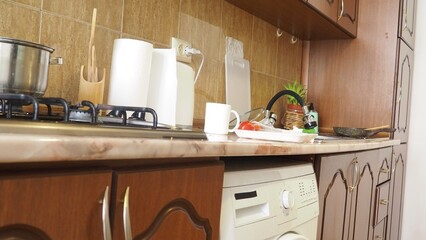 dirty dishes in the sink, plates, pans, lids. dishwashing liquid. female hands washing dirty dish...