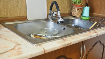 dirty dishes in the sink, plates, pans, lids. dishwashing liquid. female hands washing dirty dish holding soap foam sponge in the kitchen