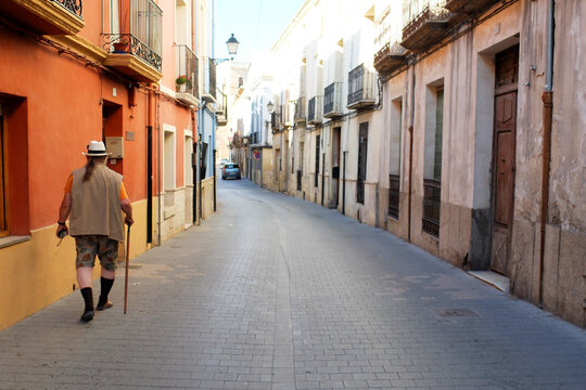 A stout German tourist walks through a colourfull street in Castalla, Spain.