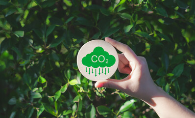 Reduce CO2 emission concept. A hand holds a green CO2 emissions symbol, representing carbon...