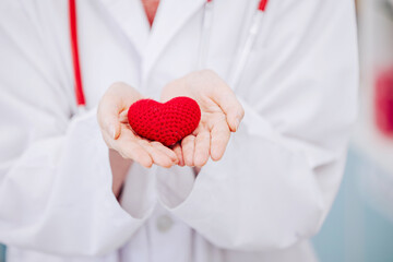 closeup doctor hand with red heart sing symbol to health protect, giving care and donation for saving people life.