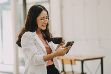 Obraz premium Portrait of a happy Asian businesswoman using mobile phone indoor, Asian businesswoman working in modern office.
