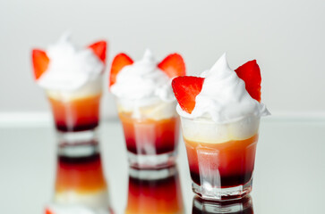 Three glasses of strawberry shot drink with whipped cream