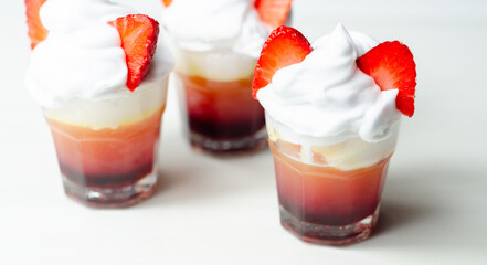 Three glasses of strawberry shot drink with whipped cream
