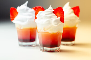 Three glasses of strawberry shot drink with whipped cream