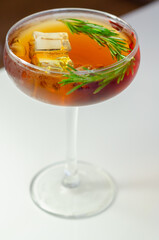 A glass of cocktail with a garnish of rosemary on top