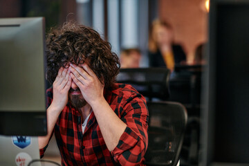 Disappointed Programmer with Messy Hair Looking at Computer Monitor in Office.