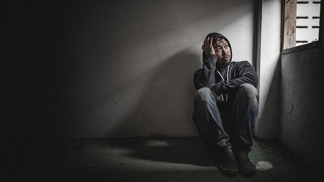 Asian man addict drug in the deserted place,A junkie feels alone in this world,Sad young man sitting in the corner of the room,People are stressed and have depression