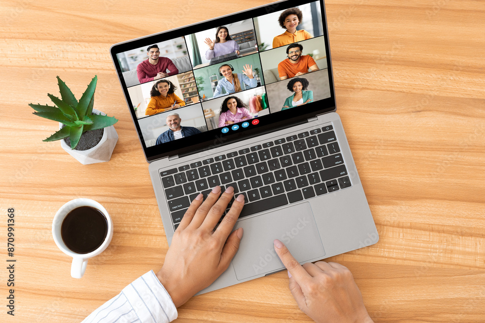 Leinwandbilder a person is sitting at a wooden desk, using a laptop to participate in a video conference. there are