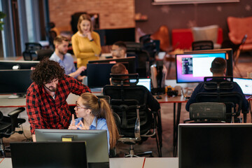 Business colleagues, a man and a woman, engage in discussing business strategies while attentively gazing at a computer monitor, epitomizing collaboration and innovation