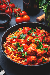 Italian spaghetti pasta in marinara sauce with meatballs, black table background, top view