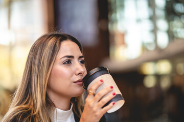 Coffee break in a public city spot: beautiful and relaxed blonde latina executive sipping coffee