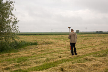 A male surveyor works with a GNSS receiver, from the back