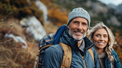 An older couple, equipped with hiking gear, smiles warmly as they trek through a beautiful mountain landscape, enjoying the natural scenery and the hiking experience together.