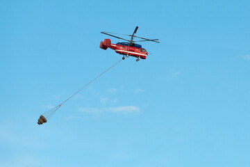Big fire rescue red colour helicopter gets water tank for damping fire bright blue sky day