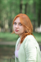 Portrait of a young beautiful red-haired girl in an urban environment.