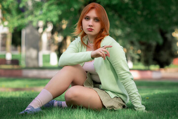 Obraz premium Portrait of a young beautiful red-haired girl in an urban environment.