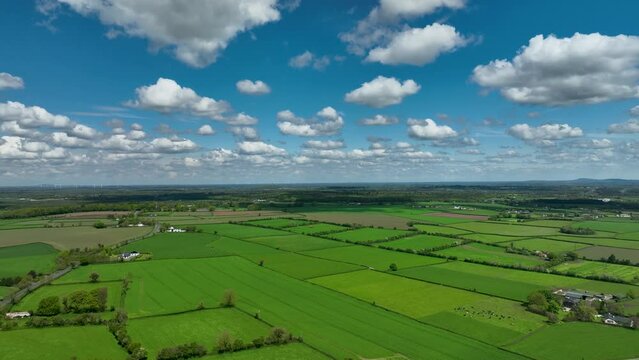 Aerial view of the expansive green agricultural landscape in County Kildare Ireland featuring fields and hedgerows under a clear blue sky with white puffy clouds.