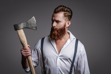 Vintage brutality guy with axe in retro suspenders. Brutal man in suspenders isolated on grey....