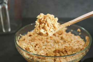 Close up of soy bean meat mince sucked up in water on a wooden spoon and glass bowl, grey marble kitchen table