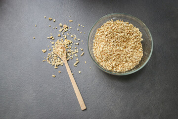 Top view of dried soy bean meat mince in a glass bowl with a wooden spoon, grey table