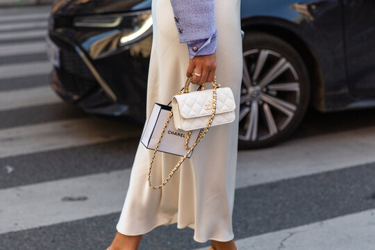 Woman in white skirt holding a white handbag from Chanel in the streets of Paris