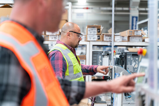 Male industrial worker working with manufacturing equipment in a production line factory - Powered by Adobe
