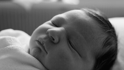 Black and white close-up of a newborn baby sleeping peacefully, highlighting the delicate features...
