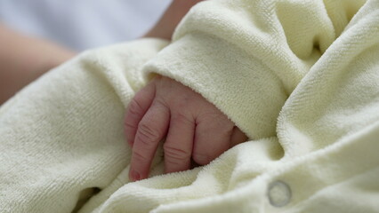 Close-up of a newborn baby's hand resting gently on a soft yellow blanket. tiny, delicate fingers, capturing the innocence and tenderness of a newborn