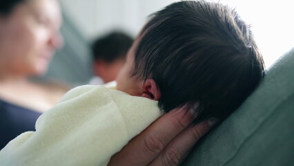 Close-up of a mother and child gazing lovingly at their newborn, with the baby comfortably cradled. blurred background emphasizes the intimate and tender moment shared by the family