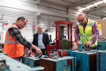 Male industrial worker working with manufacturing equipment in a factory.