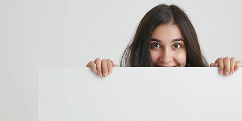 Fototapeta premium Brunette female scientist smiling behind a white edge, neutral background.