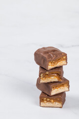 Candy bar with nougat, caramel, peanuts and hazelnuts. In milk chocolate. White  background. Copy space